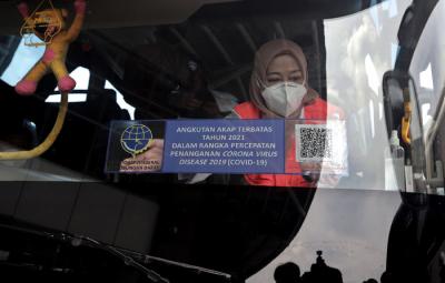 Petugas memasang stiker khusus pada armada bus yang diperbolehkan beroperasi saat masa larangan arus mudik di Terminal Pulo Gebang, Jakarta, Selasa (4/5/2021).