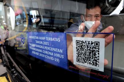 Petugas memasang stiker khusus pada armada bus yang diperbolehkan beroperasi saat masa larangan arus mudik di Terminal Pulo Gebang, Jakarta, Selasa (4/5/2021).