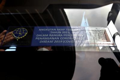 Petugas memasang stiker khusus pada armada bus yang diperbolehkan beroperasi saat masa larangan arus mudik di Terminal Pulo Gebang, Jakarta, Selasa (4/5/2021).