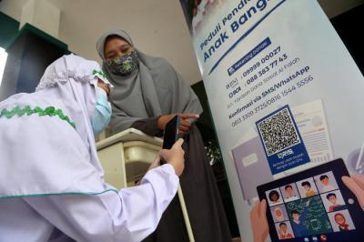 Siswa SD Al Falah Surabaya melakukan Scan QRIS ketika membayar infaq dan sedekah Ramadan di SD Al Falah Surabaya, Jawa Timur, Rabu (5/5/2021).