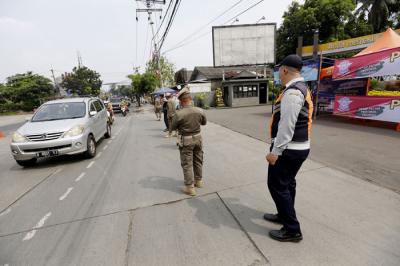Petugas gabungan mengatur lalu lintas hari pertama penyekatan larangan mudik di perbatasan Jakarta-Tangerang di Jalan Ciledug Raya, Jakarta, Kamis (6/5/2021).