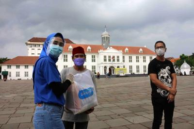 Tiket.com membagikan paket sembako di kawasan Kota Tua, Jakarta. Kamis (6/5/2021).