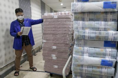 Karyawan sedang merapikan tumpukan uang tunai pecahan kecil dan besar di cash pooling Bank Mandiri, Jakarta, Jumat (7/5/2021).