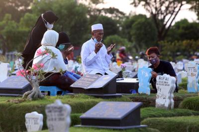 Kerabat korban Covid-19 membaca ayat-ayat suci Alquran dan berdoa ketika berziarah di makam khusus Covid-19, Keputih Surabaya, Jawa Timur, Rabu (12/5/2021).
