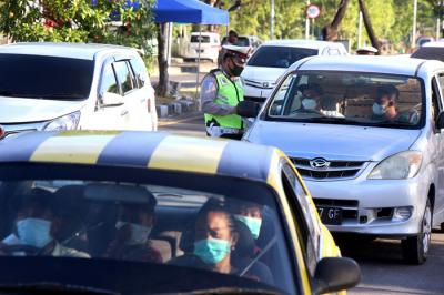 Petugas memberhentikan dan memeriksa dokumen perjalanan pengendara saat melintas di pos penyekatan pintu masuk Jembatan Suramadu, Jawa Timur, Rabu (12/5/2021).