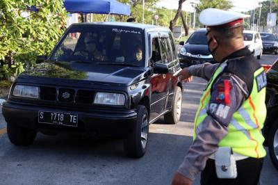 Petugas memberhentikan dan memeriksa dokumen perjalanan pengendara saat melintas di pos penyekatan pintu masuk Jembatan Suramadu, Jawa Timur, Rabu (12/5/2021).