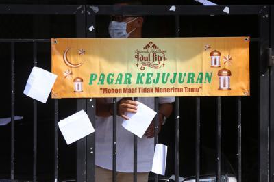 Puluhan anak dan warga mengambil amplop lebaran di Pagar Kejujuran di kediaman keluarga Trisnadi Marjan di Sidoarjo, Jawa Timur, Kamis (13/5/2021).