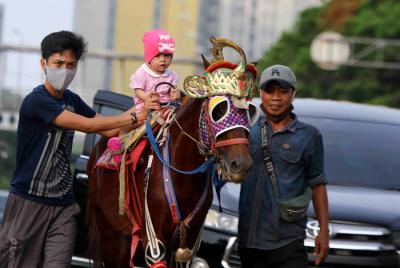 Warga memanfaat waktu liburan bersama keluarga berkeliling menunggang kuda di kawasan Kemayoran, Jakarta Pusat, Jumat (14/5/2021).