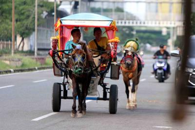 Warga memanfaat waktu liburan bersama keluarga berkeliling menunggang kuda di kawasan Kemayoran, Jakarta Pusat, Jumat (14/5/2021).