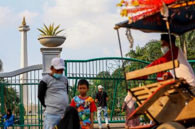 Warga di luar pagar Monumen Nasional (Monas) yang tutup di Jakarta Pusat, Sabtu (15/5/2021).