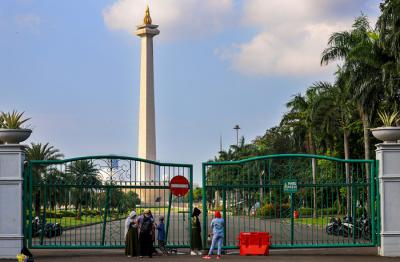 Warga di luar pagar Monumen Nasional (Monas) yang tutup di Jakarta Pusat, Sabtu (15/5/2021).
