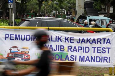 Pengendara melintasi spanduk bertuliskan himbauan kepada warga pemudik wajib test Covid-19 di Jakarta Barat, Senin (17/5/2021).