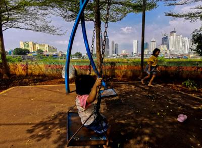 Anak-anak bermain di taman pemukiman yang berlatar belakang gedung bertingkat di Jakarta Pusat, Selasa (18/5/2021).