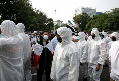 Petugas kepolisian mengenakan baju hazmat membantu pengunjuk rasa melaksanakan protokol kesehatan di depan Gedung Kedubes AS, Jakarta, Selasa (18/5/2021).