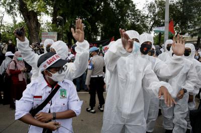 Petugas kepolisian mengenakan baju hazmat membantu pengunjuk rasa melaksanakan protokol kesehatan di depan Gedung Kedubes AS, Jakarta, Selasa (18/5/2021).