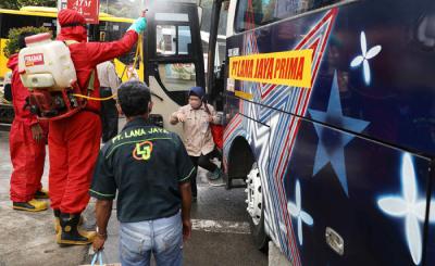 Petugas damkar menyemprotkan cairan disinfektan kepada bus yang tiba dari daerah di terminal Kampung Rambutan, Jakarta Timur, Rabu (19/5/2021).