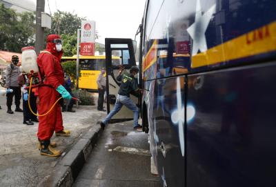 Petugas damkar menyemprotkan cairan disinfektan kepada bus yang tiba dari daerah di terminal Kampung Rambutan, Jakarta Timur, Rabu (19/5/2021).