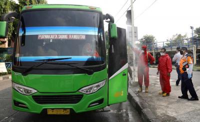 Petugas damkar menyemprotkan cairan disinfektan kepada bus yang tiba dari daerah di terminal Kampung Rambutan, Jakarta Timur, Rabu (19/5/2021).