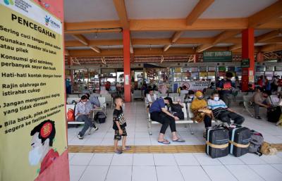 Petugas pemadam menyemprotkan cairan disinfektan kepada pemudik yang baru tiba di Terminal Kampung Rambutan, Jakarta, Rabu (19/5/2021).