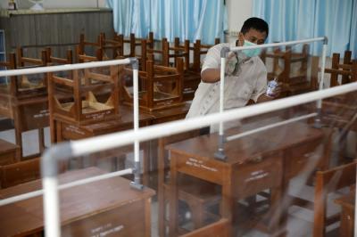 Petugas menyiapkan ruangan kelas yang akan digunakan untuk seleksi Penerimaan Peserta Didik Baru (PPDB) di SMPN 115 Jakarta, Jumat (21/5/2021).