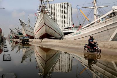 Pengendara melintasi kapal yang bersandar di Pelabuhan Sunda Kelapa, Jakart Utara, Jumat (21/5/2021).