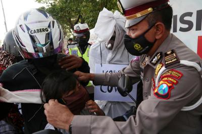 Sosok pocong korban Covid-19 jadi-jadian mengejutkan pengguna jalan saat melintas di pos penyekatan Polres Pelabuhan Tanjung Perak Surabaya, Sabtu (22/5/2021).