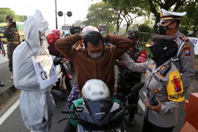 Sosok pocong korban Covid-19 jadi-jadian mengejutkan pengguna jalan saat melintas di pos penyekatan Polres Pelabuhan Tanjung Perak Surabaya, Sabtu (22/5/2021).