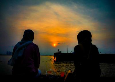 Suasana aktivitas warga sore menjelang malam di kawasan pelabuhan kaliadem, Jakarta Utara, Minggu (23/5/2021).