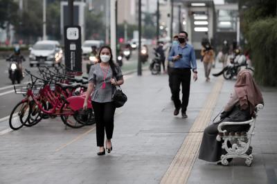 Pekerja kantor mengenakan masker berjalan di pedestrian Jalan MH Thamrin, Jakarta Pusat, Senin (24/5/2021).