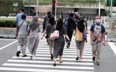Pekerja kantor mengenakan masker berjalan di pedestrian Jalan MH Thamrin, Jakarta Pusat, Senin (24/5/2021).