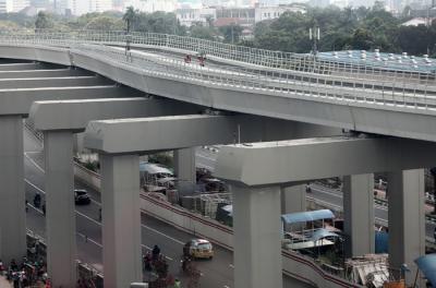 Pekerja berjalan di jalur Light Rail Transit di kawasan Jalan Rasuna Said, Jakarta, Kamis (27/5/2021).