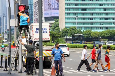 Petugas memperbaiki lampu lalu lintas di penyebrangan orang di Bundaran HI, Jakarta Pusat, Minggu (30/5/2021).