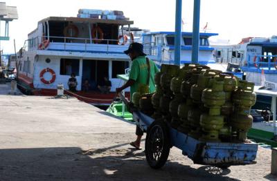 Pekerja harian lepas menurunkan gas elpji 3 kg di Pelabuhan Dermaga Pulau Panggang Provinsi DKI Jakarta, Senin (7/6/2021).