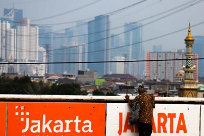 Warga saat melintas berlatar belakang gedung bertingkat di Jalan layang Tomang, Jakarta Barat, Senin (7/6/2021).