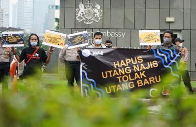 Aktivis Walhi menunjukkan poster saat menggelar aksi unjuk rasa di depan Kedubes Inggris, Kuningan, Jakarta, Jumat (11/6/2021).