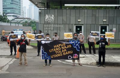 Aktivis Walhi menunjukkan poster saat menggelar aksi unjuk rasa di depan Kedubes Inggris, Kuningan, Jakarta, Jumat (11/6/2021).