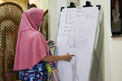 Seorang anak sedang belajar mengerjakan soal dari sekolah dibantu pengajar bimbingan belajar (bimbel) di kawasan Condet, Jakarta Timur, Jumat (11/6/2021).