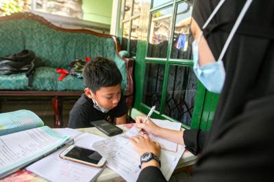 Seorang anak sedang belajar mengerjakan soal dari sekolah dibantu pengajar bimbingan belajar (bimbel) di kawasan Condet, Jakarta Timur, Jumat (11/6/2021).