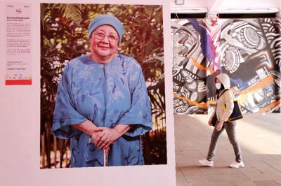 Pejalan kaki melintas di dekat pameran foto Jakpreneur Fest di Terowongan Kendal, Jakarta, Jumat (11/6/2021).