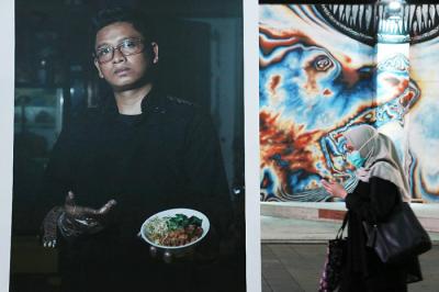 Pejalan kaki melintas di dekat pameran foto Jakpreneur Fest di Terowongan Kendal, Jakarta, Jumat (11/6/2021).