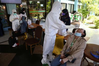 Pekerja Migran Indonesia (PMI) menjalani tes Swab PCR saat tiba di Asrama Haji Sukolilo Surabaya, Jumat (11/6/2021).