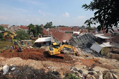 Petugas dengan menggunakan alat berat membersihkan material longsor yang menutupi aliran Kali ciputat di Perumahan Nerada Estate Ciputat, Sabtu (12/6/2021).