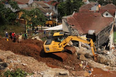 Petugas dengan menggunakan alat berat membersihkan material longsor yang menutupi aliran Kali ciputat di Perumahan Nerada Estate Ciputat, Sabtu (12/6/2021).