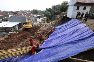 Petugas memasang terpal untuk menutupi tanah longsor di Perumahan Nerada Estate Ciputat, Tangerang Selatan, Banten, Sabtu (12/6/2021).