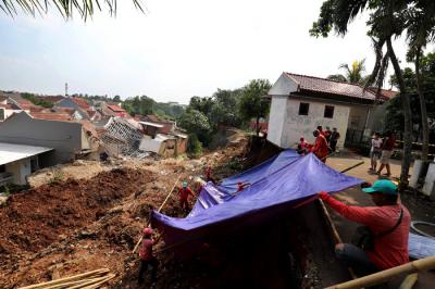 Petugas memasang terpal untuk menutupi tanah longsor di Perumahan Nerada Estate Ciputat, Tangerang Selatan, Banten, Sabtu (12/6/2021).