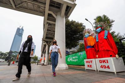 Pengunjung saat berfoto didepan ondel-ondel yang terpajang di kawasan Jalan Jenderal Sudirman, Jakarta Pusat, Minggu (20/6/2021).