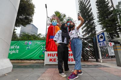 Pengunjung saat berfoto didepan ondel-ondel yang terpajang di kawasan Jalan Jenderal Sudirman, Jakarta Pusat, Minggu (20/6/2021).