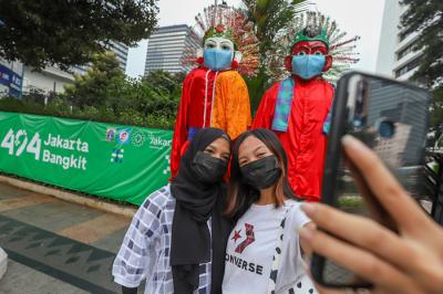 Pengunjung saat berfoto didepan ondel-ondel yang terpajang di kawasan Jalan Jenderal Sudirman, Jakarta Pusat, Minggu (20/6/2021).