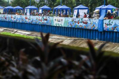 Sejumlah stand bazar ukm dengan berlatar mural cantik bertemakan kehidupan sungai di kawasan Kanal Banjir Barat, Jakarta Pusat, Senin (21/6/2021).