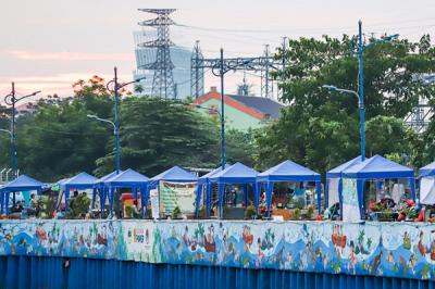 Sejumlah stand bazar ukm dengan berlatar mural cantik bertemakan kehidupan sungai di kawasan Kanal Banjir Barat, Jakarta Pusat, Senin (21/6/2021).